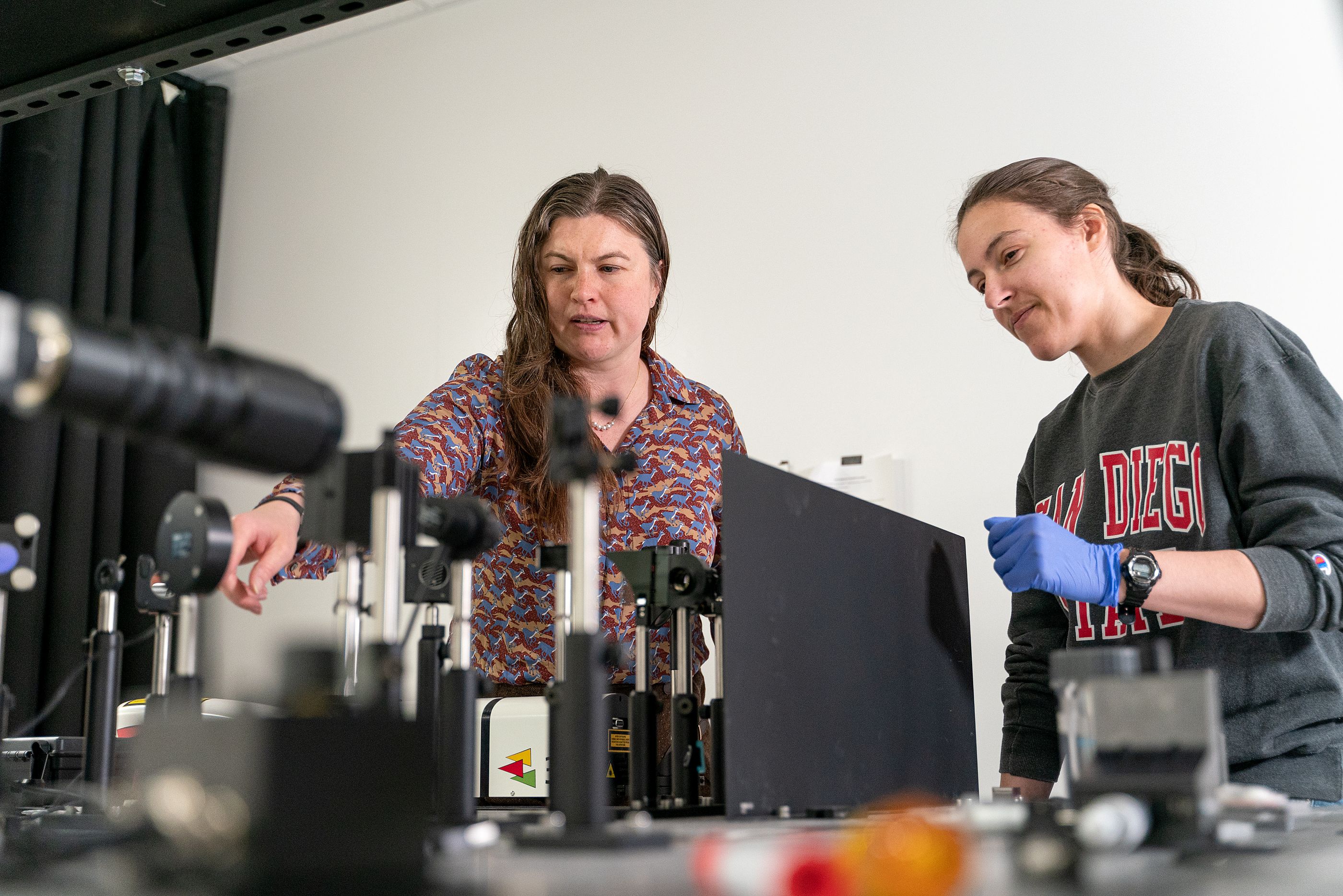 Two women working in a lab with machinery. 