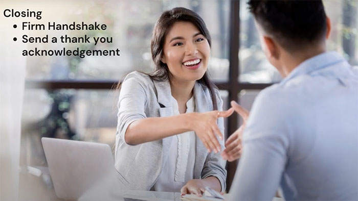 Young woman smiling while shaking hands in a professional interview setting, highlighting career readiness and closing etiquette.