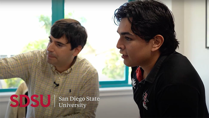 SDSU student and faculty member in discussion, reviewing academic work in a bright engineering research office.
