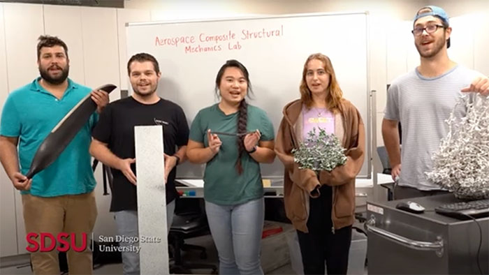 Group of SDSU students in aerospace lab holding composite materials, showcasing hands-on engineering research and teamwork.