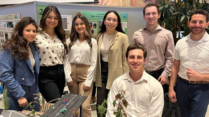 Group of engineering students presenting a sustainability project display at an academic showcase event.